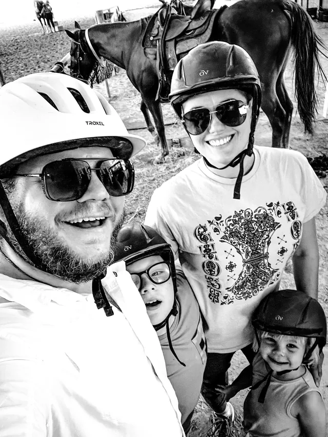 Aaron, Jacqueline, Holden, and Elliott in riding helmets, with a horse behind them