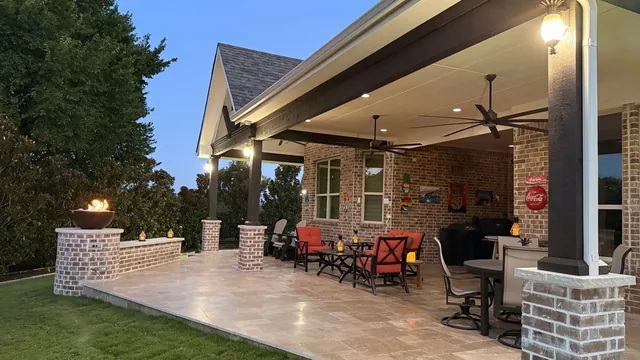 Covered patio with fireplace pillars, ceiling fans, and outdoor dining
