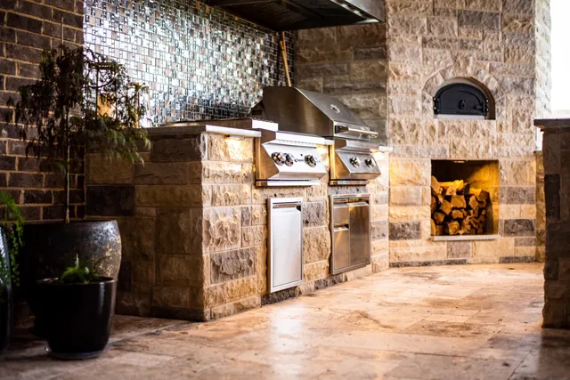 Outdoor kitchen with stone surround, built-in grill, and pizza oven